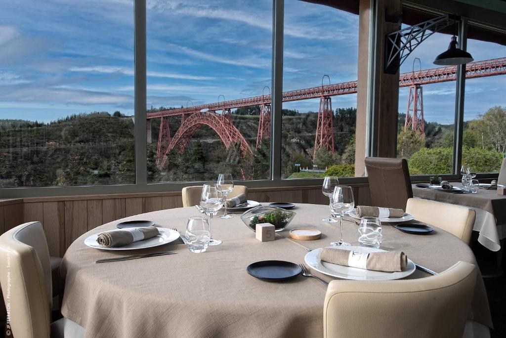 a table in a restaurant with a view of a bridge at Logis Hôtel Beau Site in Loubaresse
