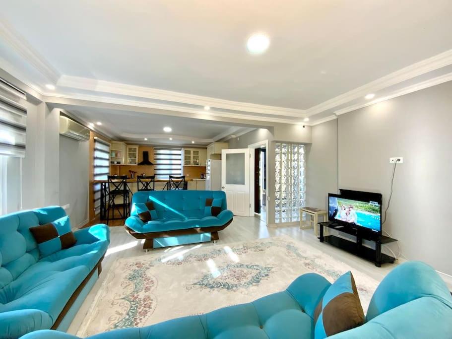 a living room with a blue couch and a television at ferah havaalanı 10 sahile 1 km yeşillikler içinde in Altınkum