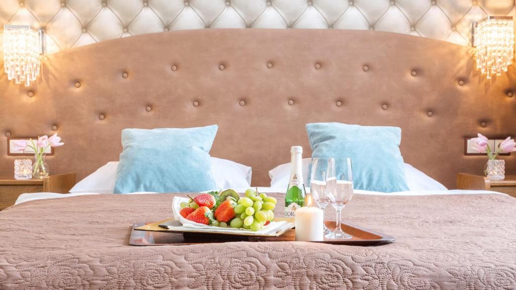 - un plateau avec des fruits et des verres à vin sur un lit dans l'établissement Hotel Sylwia, à Sośnicowice