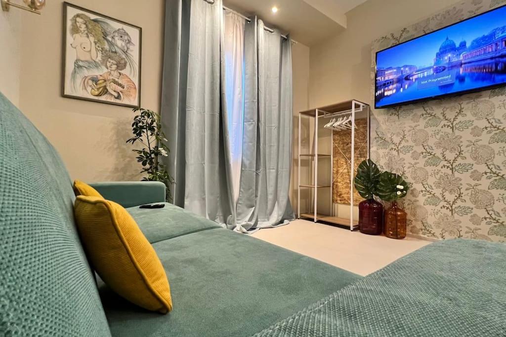 Schlafzimmer mit einem grünen Bett und einem Flachbild-TV in der Unterkunft HomingPisa - Gemini One in Pisa