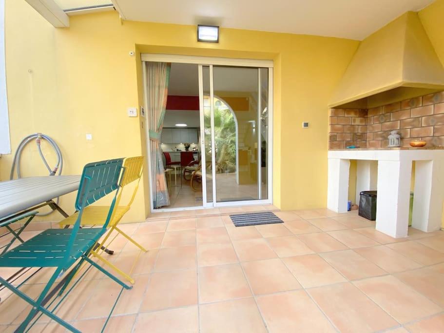 Cette chambre dispose d'une terrasse avec une table et des chaises. dans l'établissement Villa 7, La Palmeraie au village naturiste, au Cap d'Agde