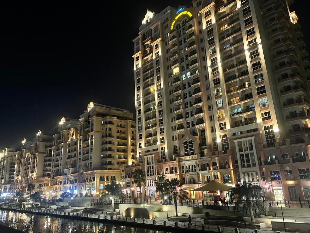 a large building at night next to a body of water at Great view, Dubai SportCity, parking included, nice Apartments in Dubai