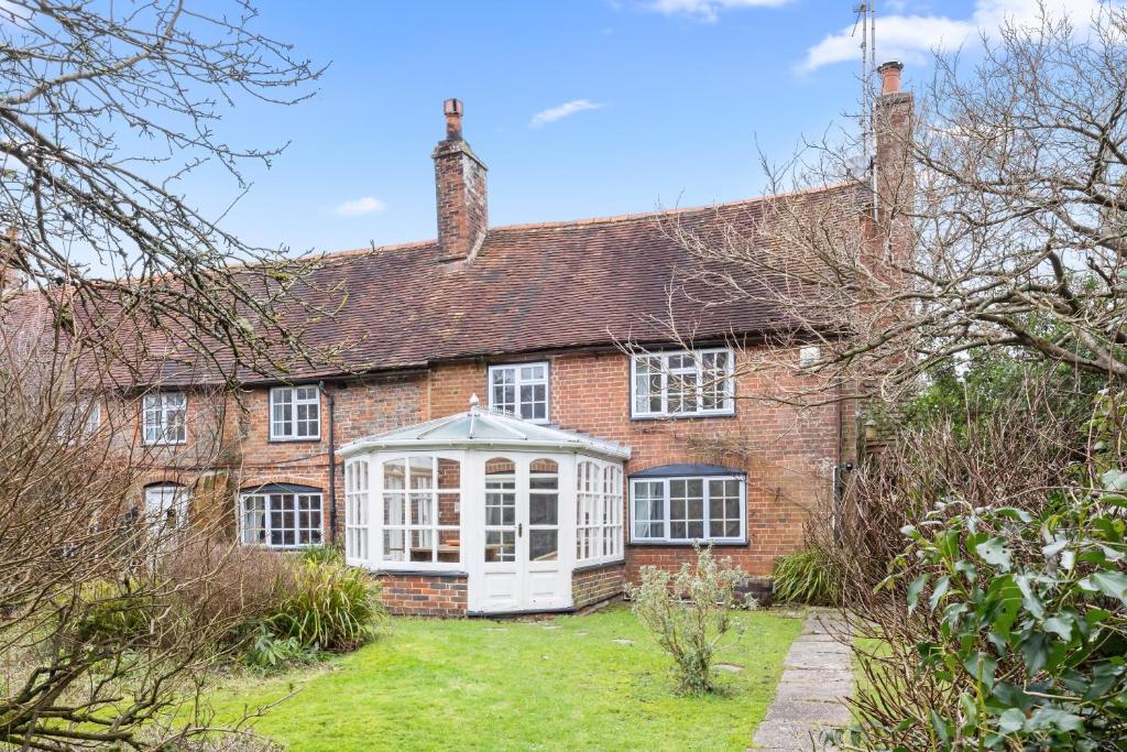 an old brick house with a greenhouse in the yard at The Milkhouse Cottage by Huluki Sussex Stays in Ashurst