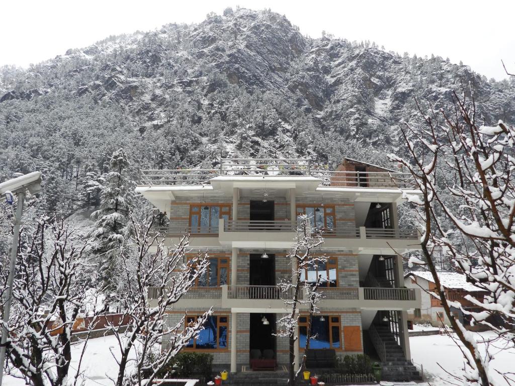 a building in front of a snow covered mountain at The Royal Orchard Kasol in Kasol
