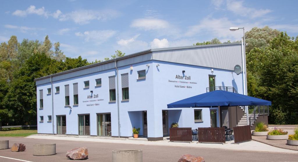 a white building with a blue umbrella in front of it at Hotel Alter Zoll in Kleinblittersdorf