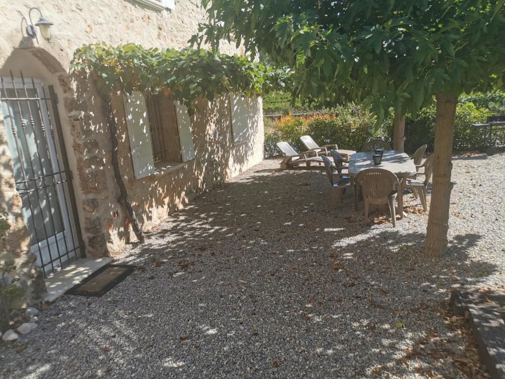 a patio with a table and chairs under a tree at Jas de Marripey in Les Arcs sur Argens