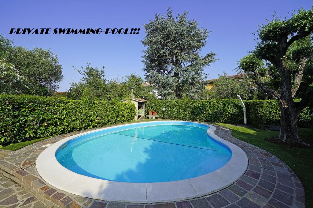 a large blue swimming pool in a yard at Villetta Quiete - Gardagate in Padenghe sul Garda