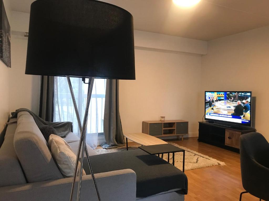 uma sala de estar com um sofá e uma televisão de ecrã plano em Paris Neuilly-sur-Seine Appartement bien situé em Neuilly-sur-Seine