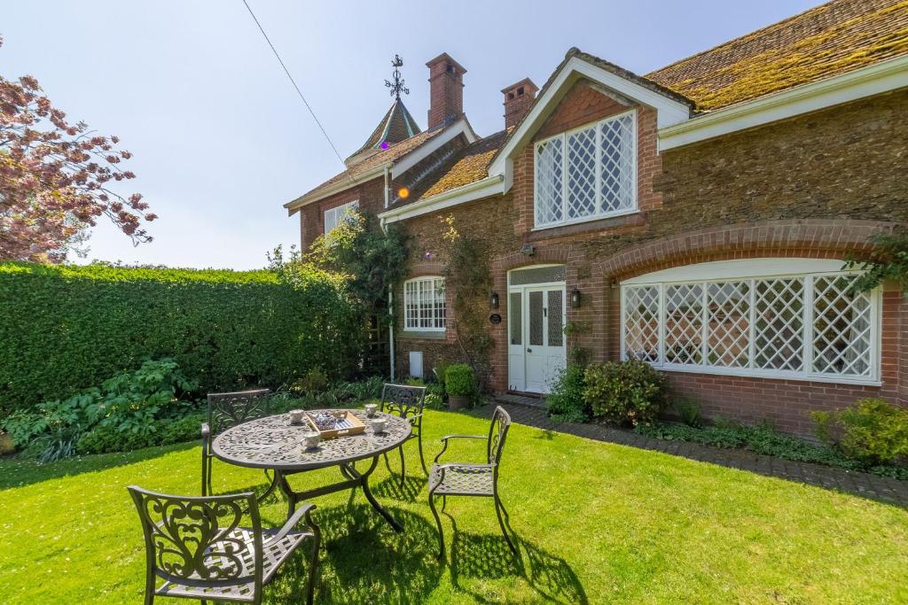 a patio with a table and chairs in front of a house at The Coach House in Flitcham