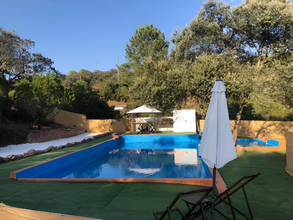 einen Pool mit einem Sonnenschirm, einem Tisch und einem Stuhl in der Unterkunft Las Chorreras del Orejón 1 in Villaviciosa de Córdoba