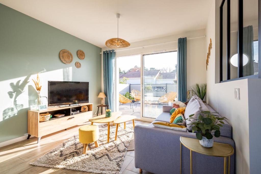 sala de estar con sofá azul y TV en Douce echappee a Andernos-les-Bains, en Andernos-les-Bains