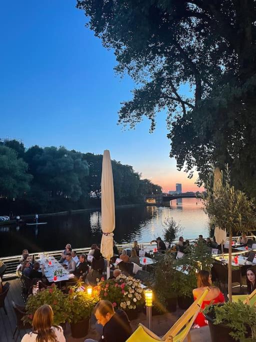 un grupo de personas sentadas en mesas junto al agua en Außenalster Penthouse Charakter, en Hamburgo