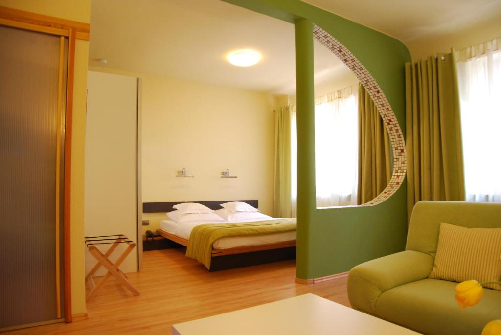 a bedroom with a bed and a chair and a mirror at Hotel Central in Göttingen