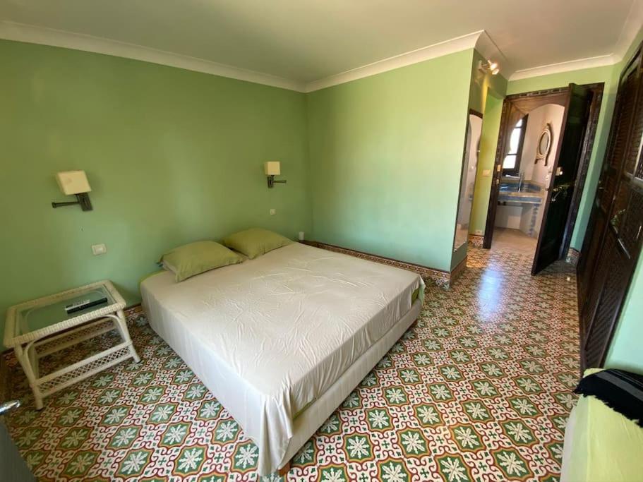 een slaapkamer met een wit bed in een groene muur bij Chambre Emeraude, Riad 9 Couple only au village naturiste in Cap d'Agde