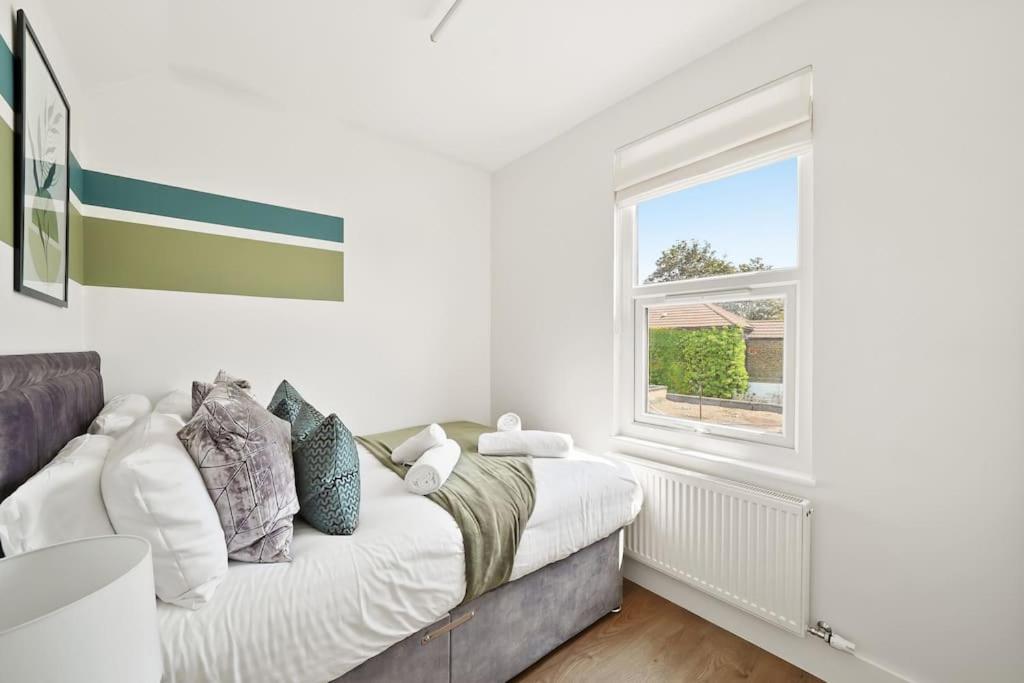 a white bedroom with a bed and a window at 2 Bed Duplex Apartment in Wimbledon in London