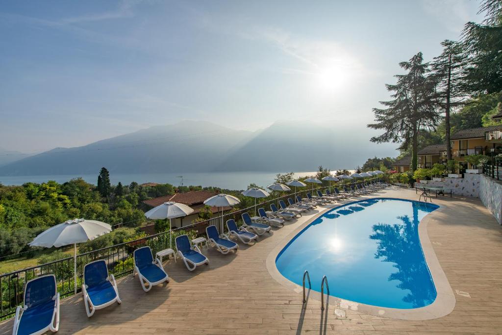 a large swimming pool with chairs and umbrellas at Residence Oasi in Limone sul Garda