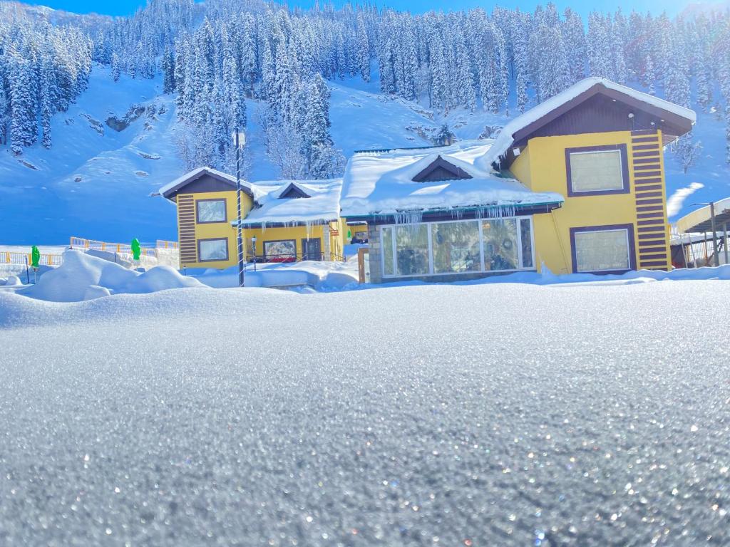 ein Haus mit Schnee auf dem Boden davor in der Unterkunft Arco Hotels & Resorts sonamarg in Sonāmarg