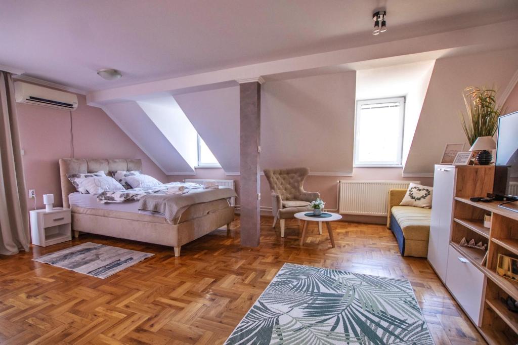een slaapkamer met een bed, een bank en een tafel bij Garden Apartment in Subotica