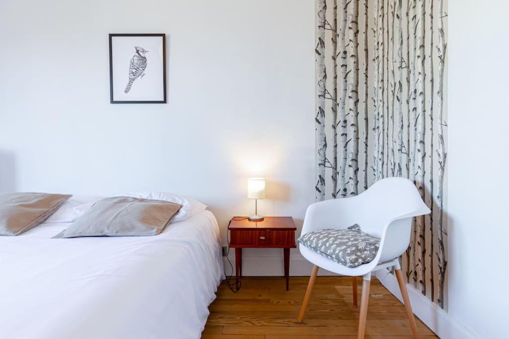um quarto com uma cama e uma cadeira ao lado de uma mesa em La grande maison-Toulouse Garonne-parking/jardin em Toulouse