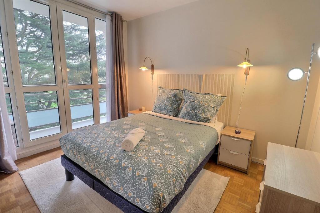 1 dormitorio con cama y ventana grande en Le Nid de l'Yvette en Chilly-Mazarin