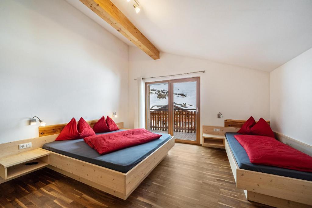 Habitación con 2 camas y almohadas rojas. en Seppnerhof Ferienwohnung Edelweiss, en Pfelders