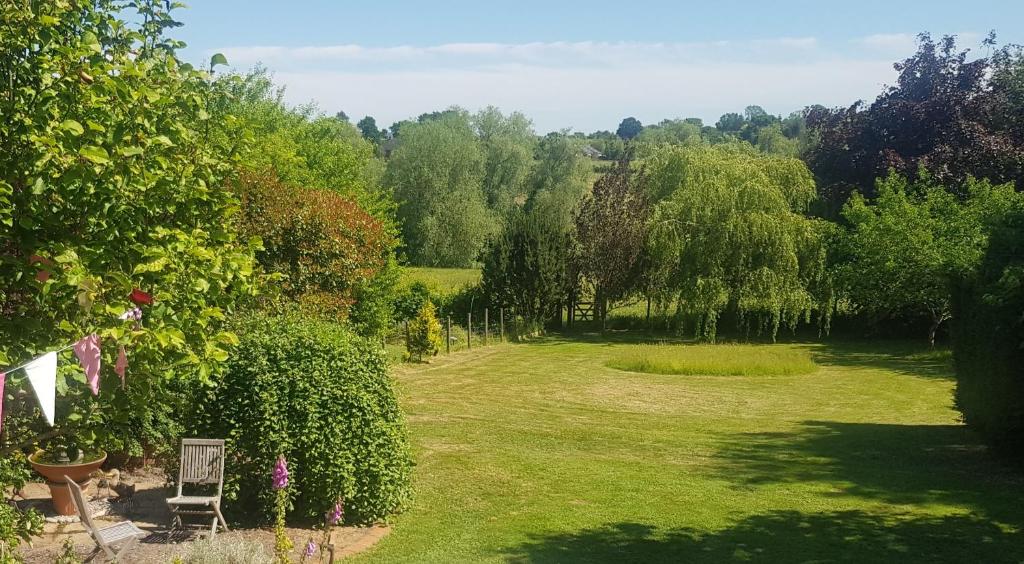 een tuin met een stoel, bomen en gras bij Redroofs in Tenbury