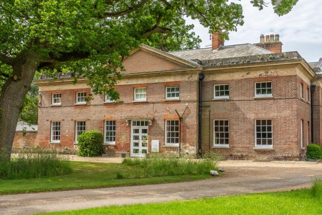 una vieja casa de ladrillo con un árbol delante en The East Wing BB en Wymondham