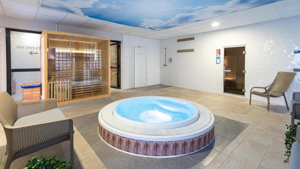 a large room with a hot tub in the middle of it at Kyriad Prestige Residence & Spa Cabourg-Dives-sur-Mer in Dives-sur-Mer