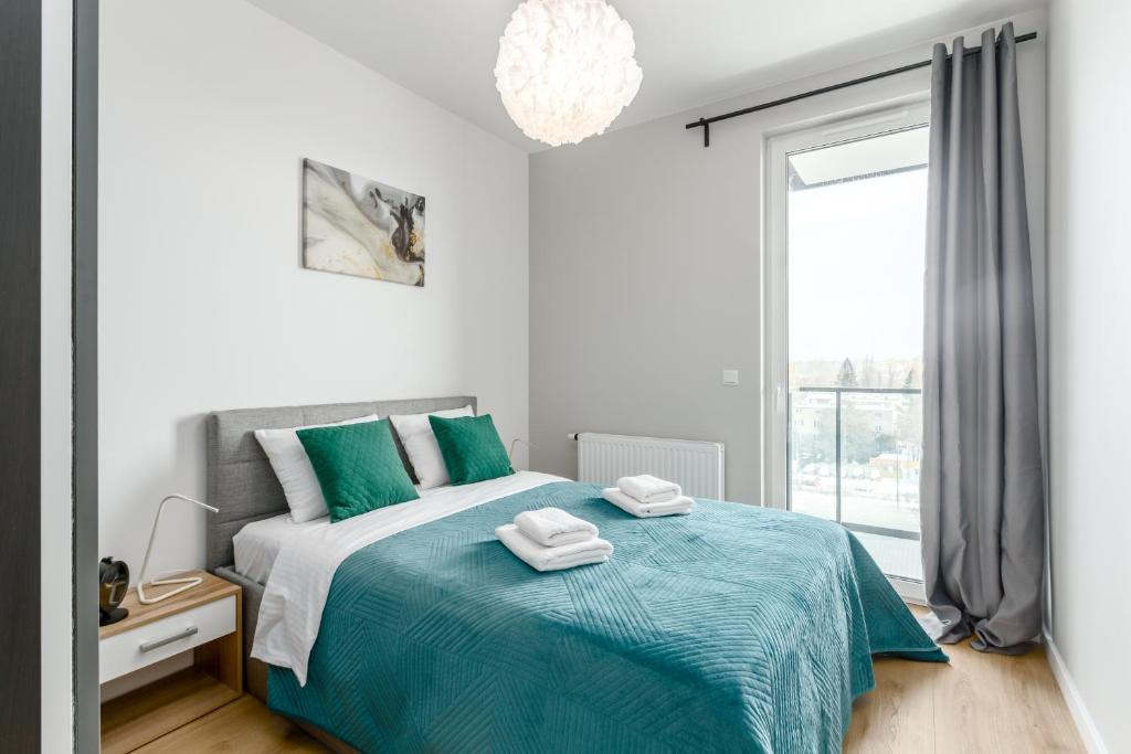 1 dormitorio con 1 cama con manta azul y ventana en Warsaw City River View en Varsovia