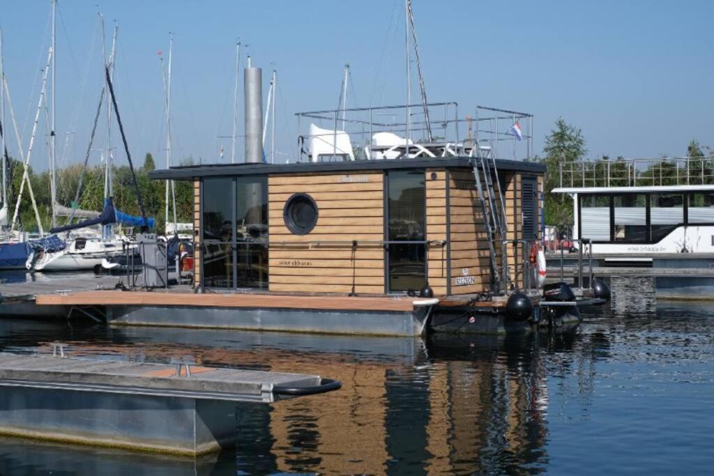 a small house on a boat in the water at Huisboot Comfort M Plus Limburg in Kinrooi