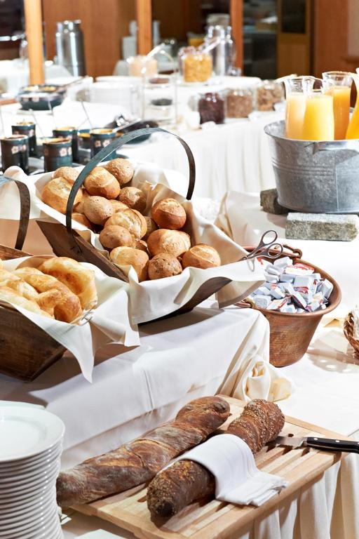 a table topped with baskets of bread and pastries at Crystal Hotel superior in St. Moritz