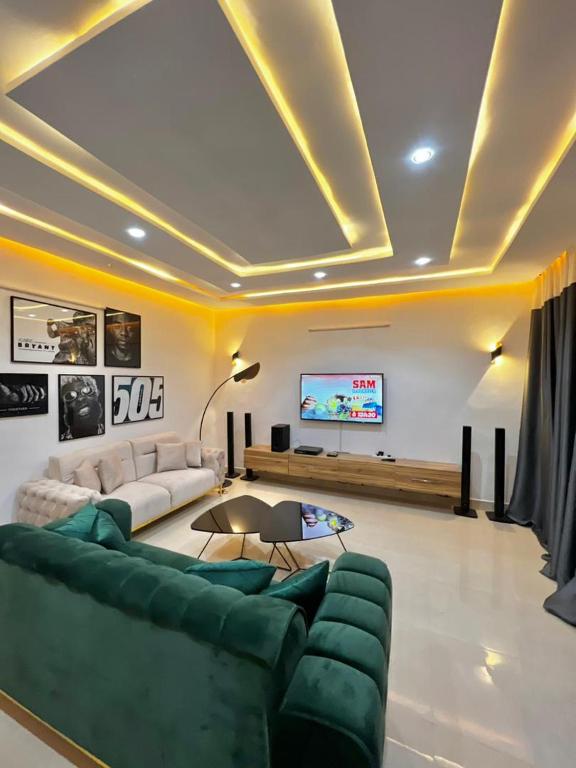 ein Wohnzimmer mit einem grünen Sofa und einem TV in der Unterkunft Timba ciné01 in Cotonou