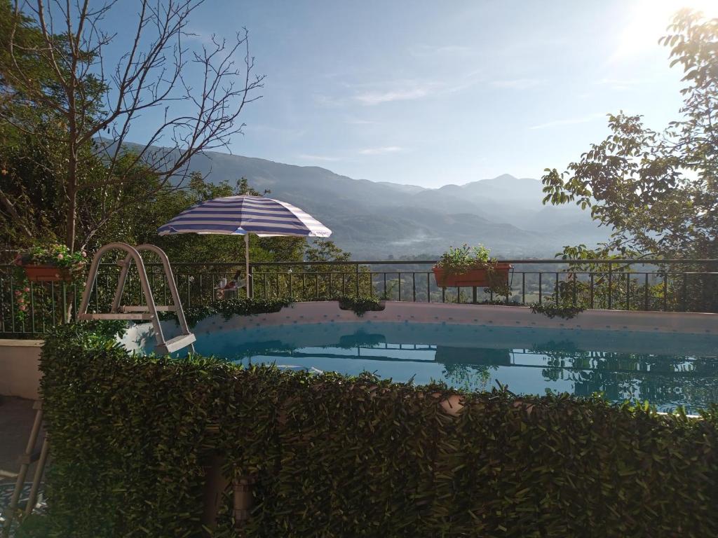 a swimming pool with an umbrella and a view of the mountains at Apartment with pool Aircon & mountain views in Gallinaro