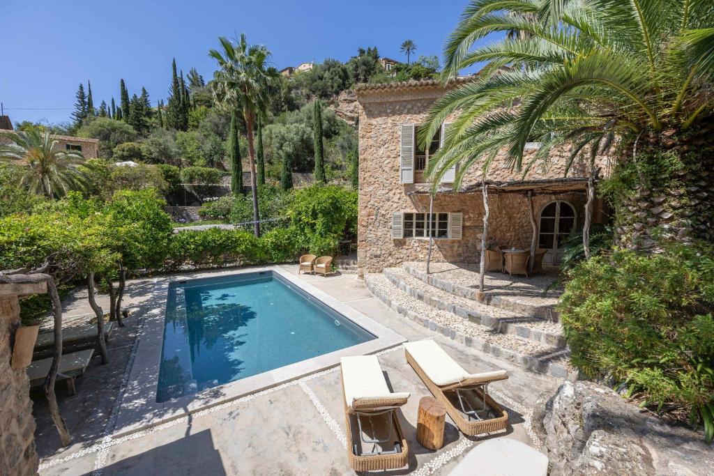 a swimming pool with two lounge chairs and a house at ES CLOT in Deia