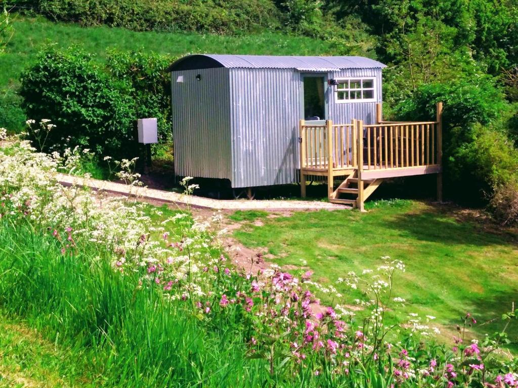 a cabin in a field with a yard with flowers at Shepherds hut in Weymouth