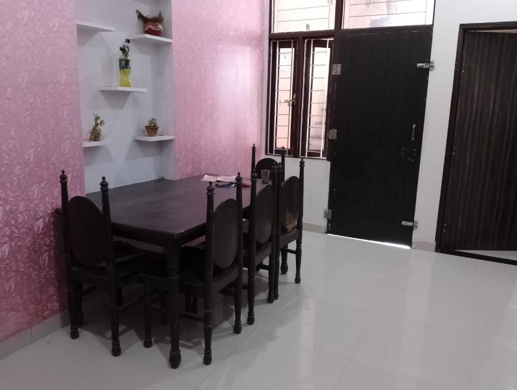 ein Esszimmer mit einem Tisch und Stühlen sowie rosafarbenen Wänden in der Unterkunft Daughter's Home in Jaipur