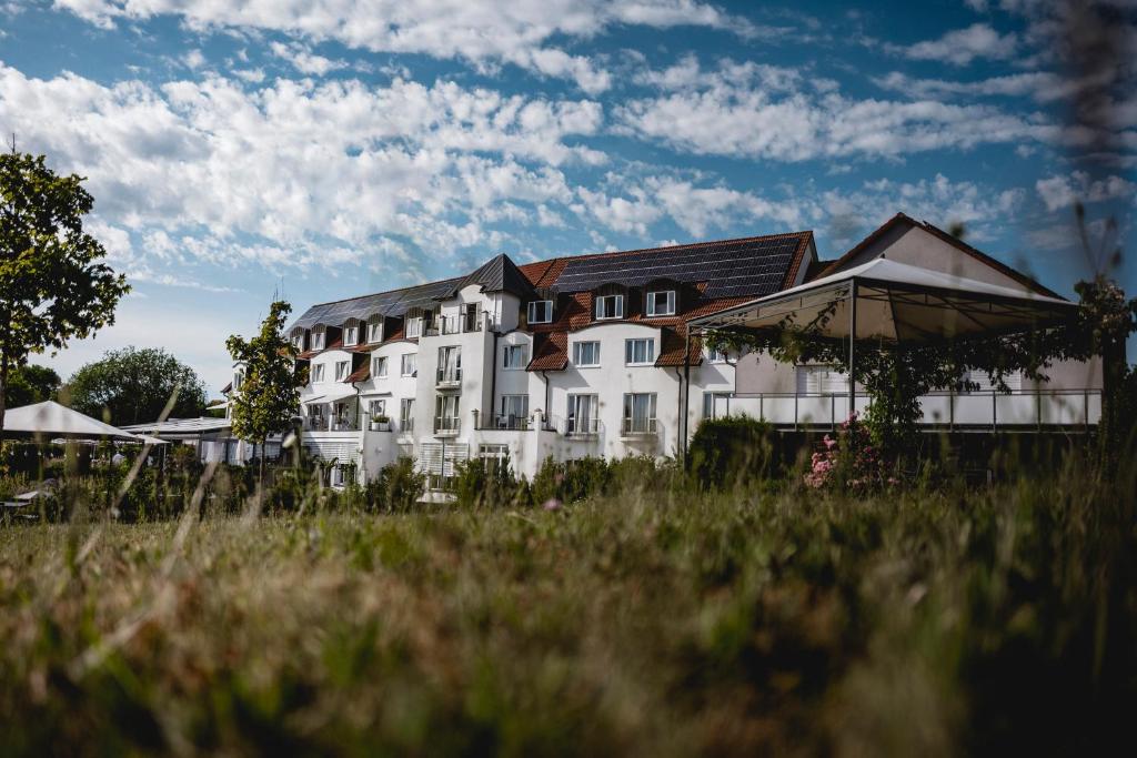 ein großes weißes Gebäude mit einem Feld davor in der Unterkunft Landhotel Rügheim in Rügheim