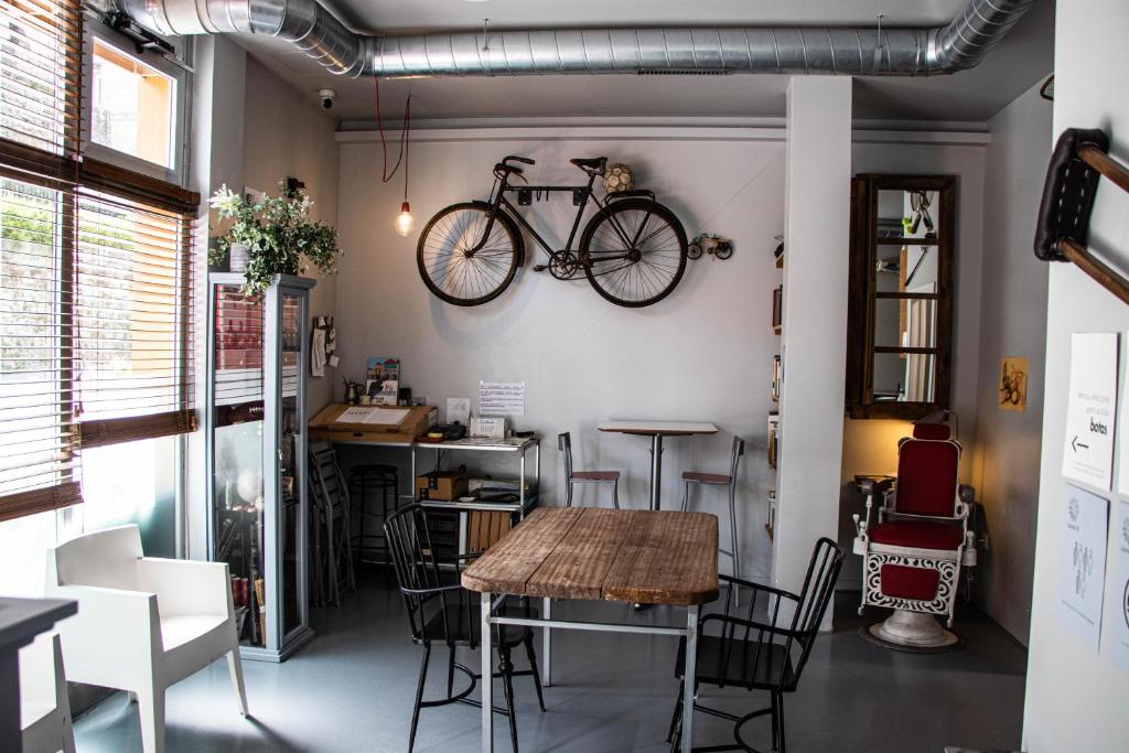 ein Zimmer mit einem Tisch und einem an der Wand hängenden Fahrrad in der Unterkunft Acolá Sport Hostel in Pontevedra