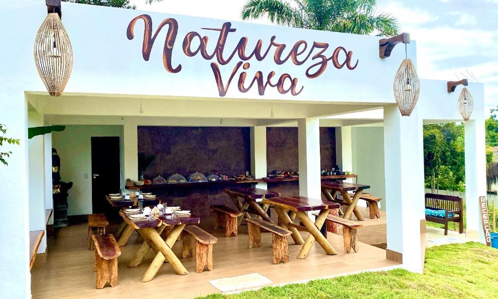 um restaurante com mesas de madeira e uma placa que lê a videira natureza em Pousada Natureza Viva em Itacaré