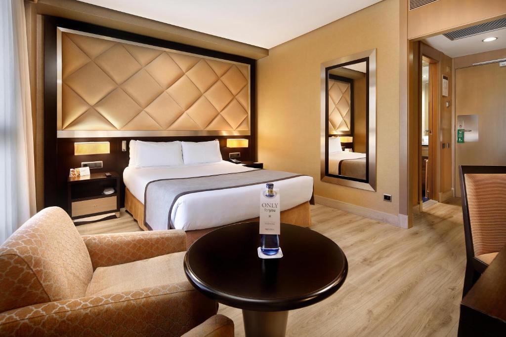 バルセロナにあるHCC サンモリッツのベッドとテーブルが備わるホテルルームです。