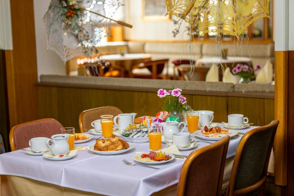a table with plates of food and orange juice at Pansion Maltar Varaždin in Varaždin