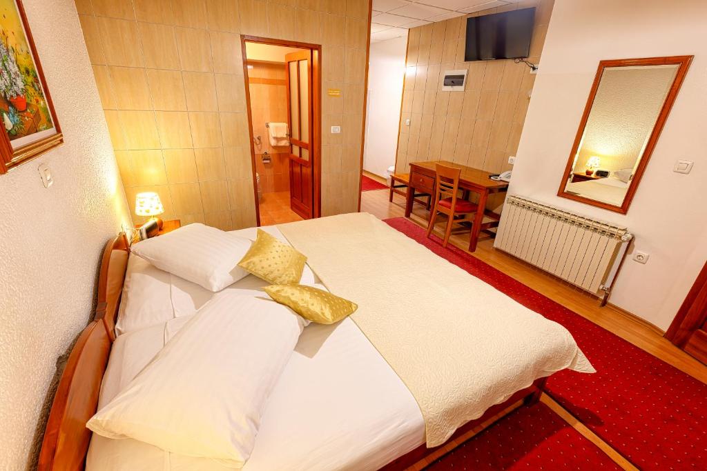 a bedroom with a bed with white sheets and yellow pillows at Pansion Maltar Varaždin in Varaždin