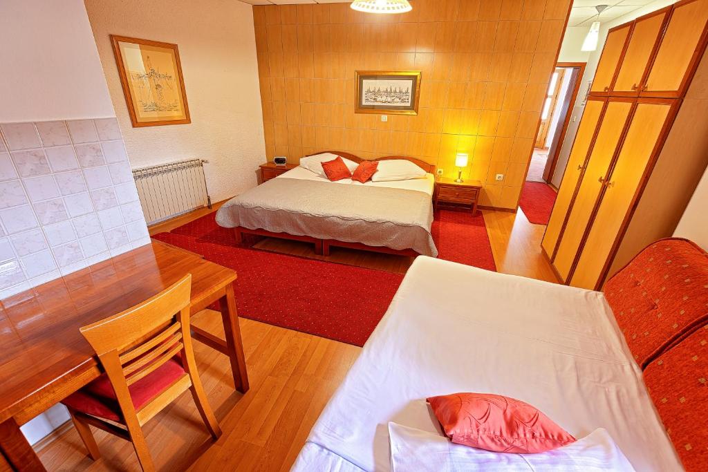 a bedroom with a bed and a desk and a table at Pansion Maltar Varaždin in Varaždin