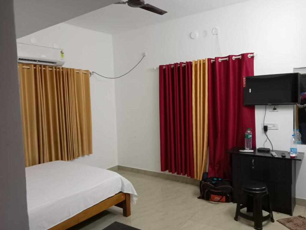 a bedroom with curtains and a bed and a television at MALANAD GUEST HOUSE THENGIPALAM CHENAKAL UNIVERCITY ROAD 