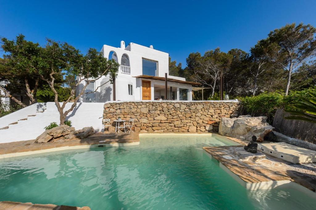 a villa with a swimming pool in front of a house at Cala Salada Sunset View in San Antonio