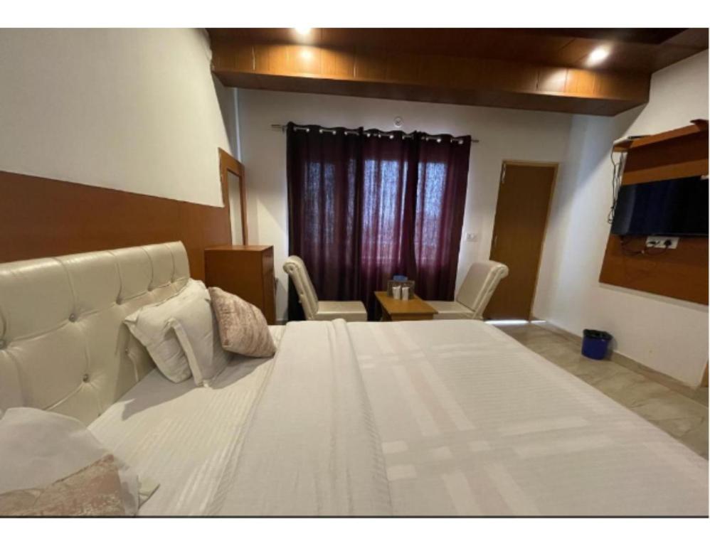a large white bed in a room with chairs at Hotel Atithi, Near Yes Bank, Mall Road, Mussoorie in Mussoorie
