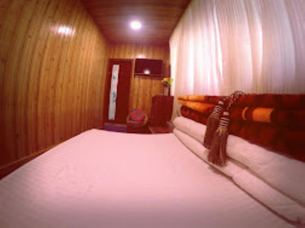 een kamer met 2 bedden in een houten kamer bij Darjeeling Inn , Darjeeling in Darjeeling