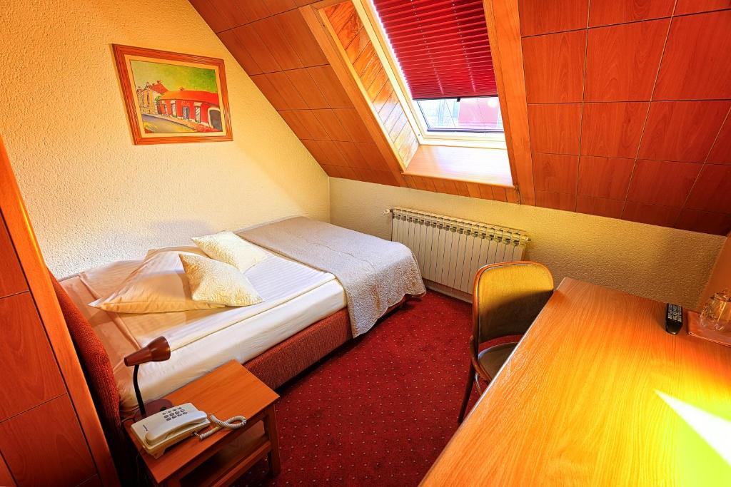 a small room with a bed and a table at Pansion Maltar Varaždin in Varaždin