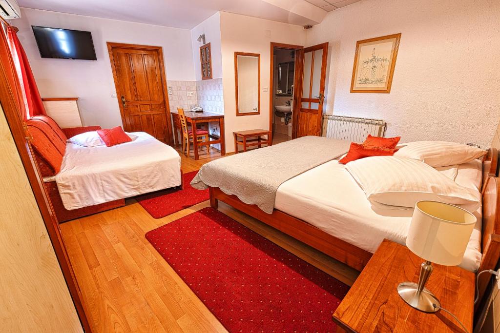 a bedroom with two beds and a red rug at Pansion Maltar Varaždin in Varaždin