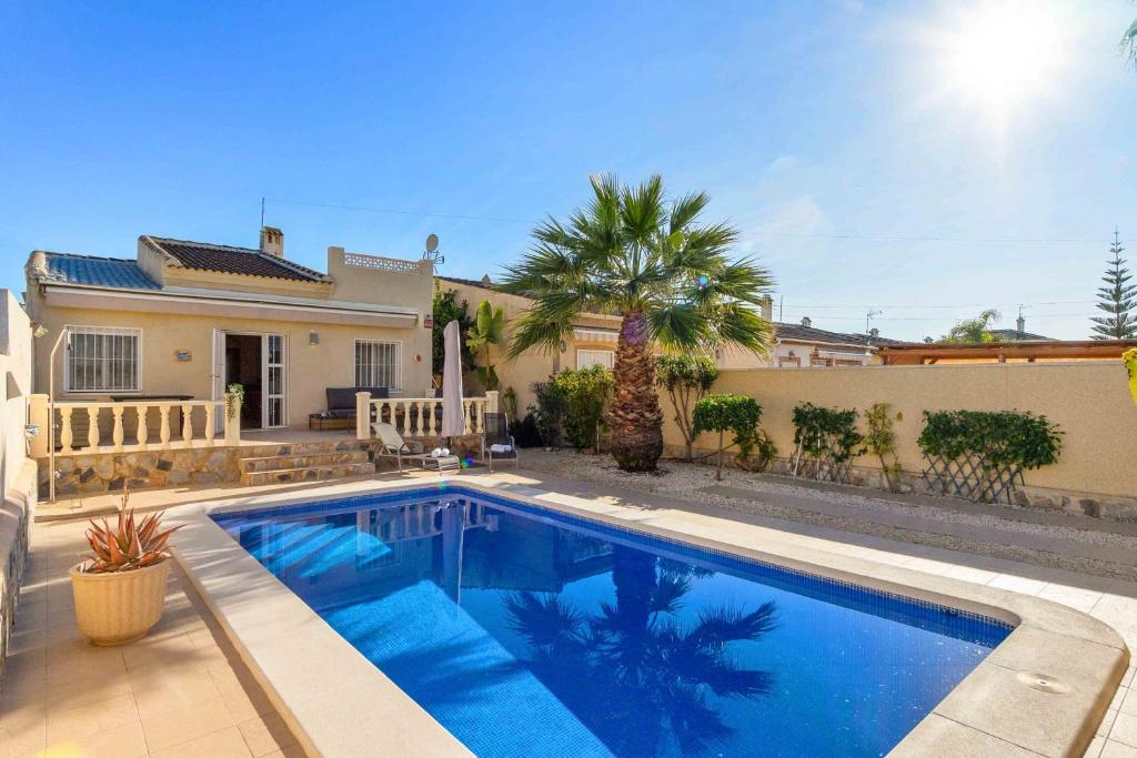 a swimming pool in front of a house at Beautiful and cozy Villa with private pool in urb, San Luis, El Chaparral, Torre in Torrevieja